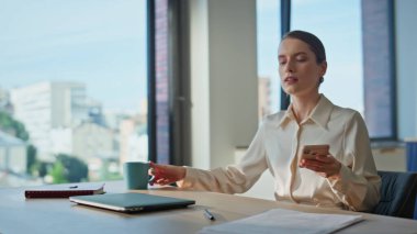 İş kadını iş yerinde oturmuş cep telefonunu yakından çekiyor. Ev mutfağında işe kahve fincanıyla başlayan ciddi bir bayan defteri açıyor. Zarif bir iş kadını masadaki belgeleri kontrol ediyor..