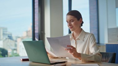 Kadın muhasebeci iş belgelerini bilgisayarda yakından inceliyor. Ev mutfağında şirket evraklarını yöneten kendine güvenen bir iş kadını. Proje üzerinde başarılı bir yönetici kendini tatmin olmuş hissediyor