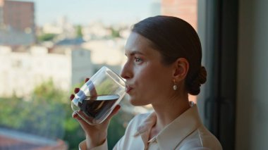 İş kadını panoramik ofis penceresinde espresso içiyor. Molada aromatik kahveyle eğlenen zarif bayan girişimcinin portresi. Gülümseyen bayan yönetici şehir manzaralı ev.