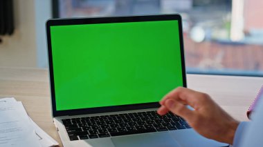 Girişimci iş yerindeki klavyede el yapımı dizüstü bilgisayara basıyor. Bilinmeyen yönetici, çalışma alanındaki yeşil ekranda eğitim videosunu açıyor. İşadamı çevrimiçi uygulamaya göz atıyor
