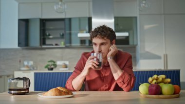 Sakin adam evde tek başına espresso içiyor. Kendini rahatlamış hissediyor. Modern mutfakta oturup sabah kahvesini yudumlayan dalgın bir adam. Düşünceli bir insan, ev mutfağında ev kahvaltısından zevk alıyor..