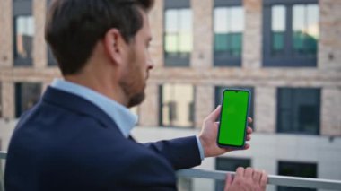 Adam dışarıdaki akıllı telefon ekranını yakından izliyor. Gevşek sakallı yönetmen Chromakey cep telefonu iş e-postalarını okuyor. Esmer işadamı şehir merkezinde yeşil ekran cep telefonu tutuyor.