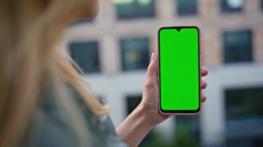 Modern şehirde yeşil ekran akıllı telefonu izleyen tanınmayan bir kadın. Krom anahtarlı telefonu tutan kız sadece SMS okuyor. Bilinmeyen serbest çalışan kadın cep telefonu bankacılığı uygulaması arıyor