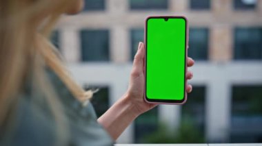 Ofis binasının yakınındaki bayan el bilgisayarı krom tuşlu akıllı telefon. Bilinmeyen bir kadın yeşil ekran cep telefonundan online uygulama açıyor. Model cep telefonunda sosyal medyada gezinen iş kadını