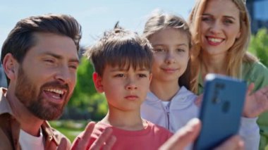 Neşeli akrabalar park portresindeki akıllı telefonu arıyor. Pozitif insanlar internette yakınlarına el sallarken görüntülü konuşma yapıyorlar. Sanal arama sırasında gülümseyen aile cep telefonu görüntüsü