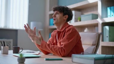 Modern işyerindeki iş krizini hissederek sorunu düşünen endişeli bir çalışan. Kıvırcık iş adamı ofis masasında iş konusunda kafa yoruyor. Sıkıntılı yönetici şirketlerin çalışma alanlarında kendini yorgun hissediyor