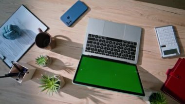 Yeşil ekran dizüstü bilgisayarı olan üst düzey teknoloji ofis masası. Modern uzaktan kumanda için aksesuarları olan profesyonel ofis. Model bilgisayar akıllı telefon kulaklıklarıyla organize çalışma alanı