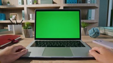 Modern apartman çalışma alanındaki yeşil ekran laptopunda Webinar izleyen öğrenci. Bilinmeyen işadamı ofisinde model bilgisayar taraması yapıyor. Organize işyerindeki adam krom anahtar monitörüne bakıyor.