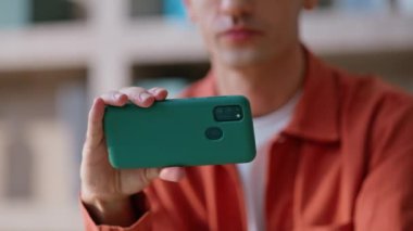 Gülümseyen serbest çalışan, uzak iş yerindeki yatay akıllı telefondan video izliyor. Neşeli adam cep telefonuyla online mesajlaşmayı seviyor. Kıvırcık işadamı cep telefonunda internet uygulamasına göz atıyor.