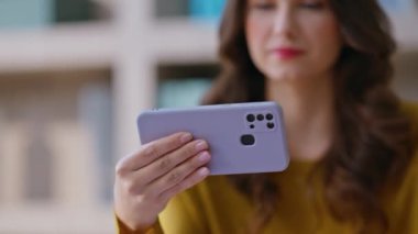 Freelancer cep telefonunda video seyrediyor. Uzak bir iş yerinde yakın çekim yapıyor. Akıllı telefondaki sosyal medyadan keyif alan olumlu bir kadın. Yatay cep telefonu tutan rahat iş kadını.