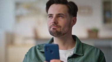 Düşünceli bir adam apartman kanepesinde cep telefonuyla mesaj bırakıyor. Mutlu genç adam evde SMS yazarken akıllı telefon ekranına bakıyor. Çatı katında cep telefonu kullanan yakışıklı esmer. 