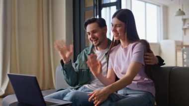 Oturma odasında dinlenirken dizüstü bilgisayarla sanal tanışma. Neşeli eşler evlerinde bilgisayar görüntülü kameralarla çevrimiçi konuşmaktan hoşlanırlar. Gülen çift video çağrısı