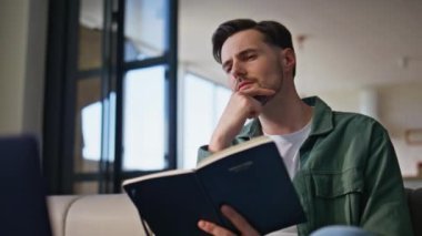 Çevrimiçi öğrenci ev ödevi yazıyor. Yakın çekim. Bilgisayara odaklanmış bir adam eğitici videodan notlar alıyor. Erkek uzaktan çalışan planlama projesi. Konforlu dairedeki not defterine bilgi ekleniyor.