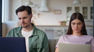 Ev içi iç çekimde dizüstü bilgisayarlar kullanarak çalışan çift. Mutlu eş bilgisayarda yazarken birbirlerine gülümseyerek bakıyor. Serbest Çalışanlar çifti İnternet 'te geziniyor ve online işten keyif alıyorlar
