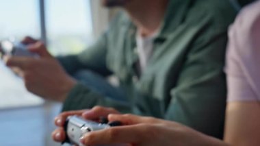 İki kişi, oturma odasındaki kanepenin kapanış düğmelerine basıyor. Heyecanlı, sevinçli kız elinde joystickle sevinen yarışmacı daire kanepesi kazandı. Mutlu duygusal oyuncular birlikte eğlenir.