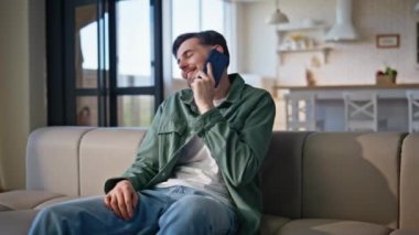 Özel mülk kanepesinde cep telefonuyla konuşan gülen adam. Dinlenen, akıllı telefondan iletişim kuran, rahat stüdyoda hikayeler anlatan adam. Mutlu öğrenci kanepede dinleniyor. Keyifli sohbetler. 