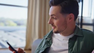 Pozitif adam, yakın çekimde akıllı telefon uyarısını kontrol ediyor. Neşeli koca karısına cep telefonunu gösteriyor. Kazanan iki kişi duygusal tepki verir. Mutlu çift zaferi kutluyor.