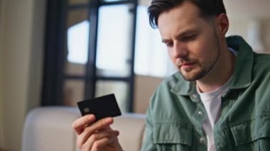 Kredi kartı tutan adam, yakın çekimde alışveriş yapıyor. Odaklanmış erkek, açık havada online ödeme yapıyor. Klavyede dizüstü bilgisayarla yazı yazan yakışıklı bir adam. İş adamı kanepede alışveriş yapıyor.