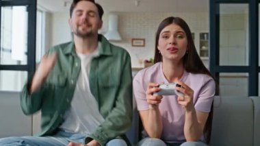 Duygusal çift, evdeki kanepe kapanışında online video oyunu oynayan konsol tuşlarına basıyor. Oyun kazanan, elinde kumanda kolu tutan heyecanlı aktif adam. Üzgün kadın kaybediyor. Modern hobi konsepti