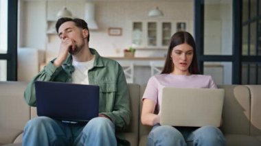Oturma odasının iç kısımlarında bilgisayar kullanan çevrimiçi yöneticiler. Yorgun, esneyen kadın migren ağrısı çekiyor. Dizüstü bilgisayar arayan yorgun insanlar birlikte kanepede iş birliği yapıyorlar. Daktilo eden yorgun kadın.