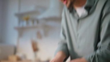 Erkek eller mutfakta sebze doğruyor. Neşeli adam kulaklıkla dans edip organik öğle yemeği için taze malzemeler hazırlıyor. Mutlu erkek, kablosuz kulaklıkla müzik dinlemeyi sever. 