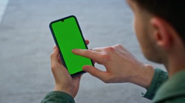 Öğrenci el ele tutuşan kromakey akıllı telefon. Bilinmeyen adam evde internete bakan sahte telefon ağı izliyor. Tıraşsız adam dairede yeşil ekran cep telefonunu parmaklıyor.