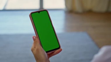 Açık yeşil ekranlı cep telefonuna dokunuyor. Bilinmeyen bir kadın büyük pencerelerde krom tuşlu akıllı telefon tutuyor. Dairede kız el taraması Model cep telefonu uygulaması