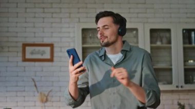 Yemek pişiren adam akıllı telefon gibi görünüyor. Mutfakta müziği kapatıyor. Kulaklıkla şarkı dinleyen mutlu adam ev mutfağında eğleniyor. Gülümseyen esmer, kulaklıklı, kahvaltı için salata hazırlayan. 
