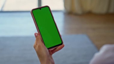 Yeşil ekran akıllı telefonu tutan kadın ev kamerasında dinleniyor. Tanımlanamayan kadın kullanıcı içerideki cep telefonunda internetten film izliyor. Dairedeki Chromakey cep telefonundan mesaj okuyan kız