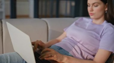 Rahat bayan, evdeki kanepede dizüstü bilgisayarla e-posta yolluyor. Düşünceli genç bir kadın evde bilgisayar işi yapıyor. Uzaktan kumandalı apartman koltuğu projesinden esinlenerek 