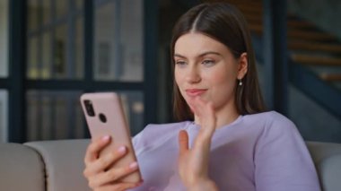 Rahat ev ortamında cep telefonu koltuğu kullanan neşeli bir esmer. Mutlu kadın rahat oturma odasında iletişim akıllı telefonuyla eğleniyor. Sakin bir bayan koltukta cep telefonu uygulamasına bakıyor.