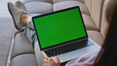 Kullanıcı Chromakey laptop dokunmatik dokunmatik dokunmatik dokunmatik daire kanepe yakın çekim soğutma. Evde yeşil ekran bilgisayarda çalışan tanınmamış bir kadın serbest yazar. Kanepede oyuncak kullanarak internetten okuyan kız öğrenci. 