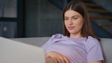 Dizüstü bilgisayarda film seyreden gülümseyen kız kanepeye yakın oturuyor. Bilgisayarda çalışan mutlu kadın rahat bir apartman dairesinde Webinar 'ın keyfini çıkarıyor. Rahat bayan internet sitesi hafta sonu yalnız başına dinleniyor. 