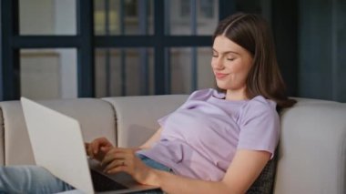 Dinlenen kız bilgisayardan mesaj atıyor, kanepeye oturuyor, yakın plan çekiyor. Hayalperest kadın dizüstü bilgisayarda e-posta hazırlıyor rahat bir dairede hafta sonunun tadını çıkarıyor. Rahat bayan internet sitesi yalnız takılıyor. 