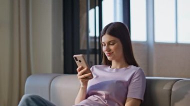 Rahat bir gencin elinde cep telefonu, rahat bir koltukta tek başına oturması. Rahat ev koltuğunda akıllı telefon izleyen gülümseyen kadın. Mutlu kadın serbest çalışan dairede rahatlatıcı cep telefonu mesajları okuyor.