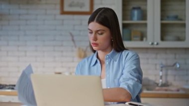 Bilgisayarda zoom toplantısında konuşan belgeleri inceleyen videolu bir kız. Mutfak masasında oturan mutlu bayan web kamerasıyla sohbet ediyor. Gülümseyen kadın video çağrısında proje detaylarını açıklıyor