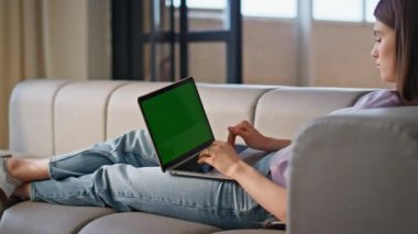 Kanepe yakınında yeşil ekran dizüstü bilgisayar kullanan bir kız. Çevrimiçi öğrenci merkez ofiste uzaktan klavye yazma eğitimi alıyor. Rahatlamış kadın yönetici yalan söyleyen kanepe mesajları atıyor. Uzak iş yeri kavramı 