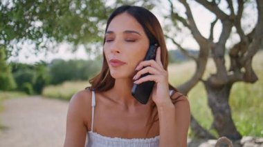 Sinirli kız cep telefonu araması buketi yakından tutuyor. Endişeli kadın doğada cep telefonu sohbeti yapıyor. Sinirli esmer kadın akıllı telefondan konuşuyor. Stresli bir şekilde bankta oturuyor. Güzel bahçe yalnız.