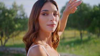 Kırsal kesimdeki bir kız, güneş ışığını yeşil bahçeyle kaplıyor. Rahat esmer, temiz bahar havasının keyfini çıkarıyor. Güzel yeşillik pozu veren neşeli kadın modeli yalnız görünüyor.