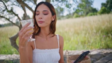 Açık hava çekiminde elinde akıllı telefon tutan içki içen kadın. Romantik manken portakal suyunu tek başına ağacın altında içiyor. Yaz tatilinde cep telefonu kullanan güzel, rahat bir bayan. 