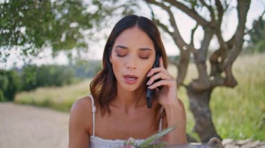 Ormanda dinlenen, cep telefonuyla konuşan ciddi bir bayan. Esmer, genç bir kadın, doğada akıllı telefon kullandığı için gergin. Endişeli model cep telefonuyla ağacın altında oturuyor. Teknoloji konsepti