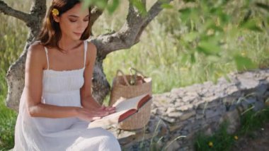 Esmer model, Meadow Doğa 'da kitap okuyor. Yakın plan. Genç, güzel bir kadın sayfalarca buğday tarlası pikniğinden memnun. Kadınsı bayan yaz manzarasını tek başına dinlendiriyor. En sevdiği romanı yazıyor.