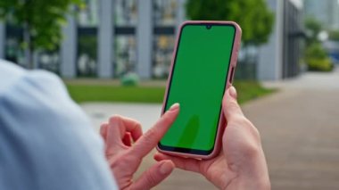 İş kadını elleri yeşil ekran akıllı telefonuna dokunuyor. Şehir caddesinde kapalı duruyor. Tanımlanamayan bir kadın cep telefonuyla internette geziniyor. Dışarıda krom telefondan sosyal medyayı izleyen bir bayan var..