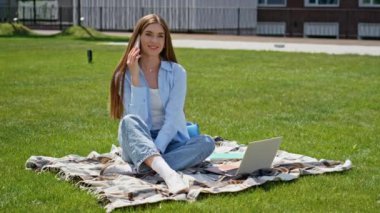 Kampüsün bahçesinde oturan neşeli kız cep telefonunu arıyor. Yeşil çimenlerin üzerinde telefonla konuşmaktan hoşlanan gülümseyen kadın öğrenci ders arası veriyor. Akıllı telefondan konuşan mutlu bayan laptopla battaniyeyi rahatlatıyor..