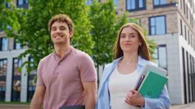 Kendine güvenen meslektaşlar, kapalı kapılar ardında güneşli bir günün tadını çıkaran defterlerle birlikte yürüyorlar. İki iş adamı modern binanın yakınlarında geziniyor. Kameraya bakıyor. Ders çalışmak için kitap taşıyan genç öğrenciler.