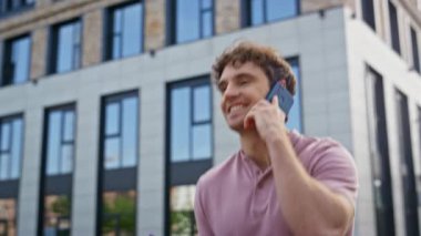 Modern şehir binasının yakınında akıllı telefondan konuşan pozitif öğrenci. Kendine güvenen bir profesyonel şehir ortamında sıradan bir gezintide cep telefonu sohbeti yapıyor. Mutlu adam telefonu arıyor..