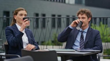 Rahat iş ortakları belediye binasının terasında birlikte kahve içiyorlar. Takım elbiseli iş arkadaşları dışarıda kahve içerek eğleniyorlar. Resmi olmayan toplantıda gülümseyen mutlu profesyoneller..