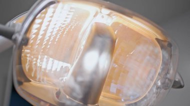 Klinikteki muayenede parlayan diş lambası. Sağlık hizmetlerinde ışıklandırma sağlayan tıbbi ekipmanlar. Modern diş hekimliği bürosunda stomatoloji tedavi prosedürleri için kullanılan ışık.