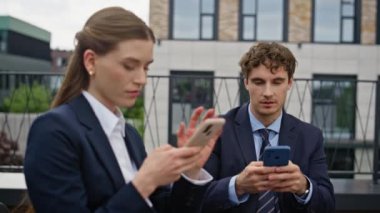 Ofis terasında çalışan akıllı telefonları birbirine bağlayan iş adamları. İş kadını açık hava ortamında cep telefonlarını kontrol ediyor. Profesyoneller sokaktaki dijital bağlantıya konsantre oluyor.