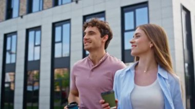 Neşeli kadın elinde kahve fincanlarıyla dışarı çıkıyor. Gülümseyen arkadaşlar modern mimarinin yanında gündelik yürüyüşün keyfini çıkarıyorlar. Rahatlamış hissediyorlar. Şehir sokağında çalışmaktan keyif alan mutlu meslektaşlar.